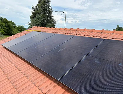 Une installation résidentielle de quatre panneaux photovoltaïques à haute efficacité, alignés avec précision sur un toit en tuiles terre cuite, réalisée par Charnet Électricité Générale.