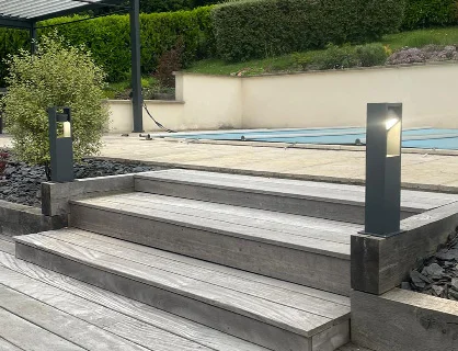Installation d'éclairage extérieur moderne avec bornes LED autour d'une terrasse de piscine à Vichy par Charnet Électricité Générale.