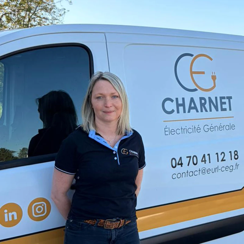 Mme Charnet, devant son véhicule utilitaire floqué au nom de Charnet Électricité Générale à Vichy.
