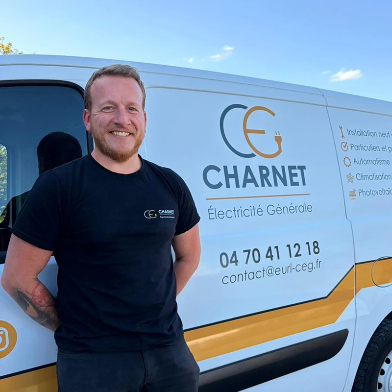 Artisan électricien, devant son véhicule utilitaire floqué au nom de Charnet Électricité Générale à Vichy.