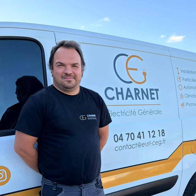 Artisan électricien, devant son véhicule utilitaire floqué au nom de Charnet Électricité Générale à Vichy.