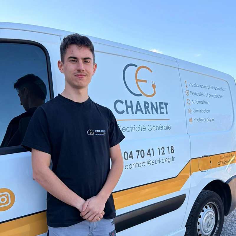 Artisan électricien, devant son véhicule utilitaire floqué au nom de Charnet Électricité Générale à Vichy.