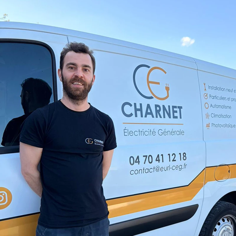Artisan électricien, devant son véhicule utilitaire floqué au nom de Charnet Électricité Générale à Vichy.